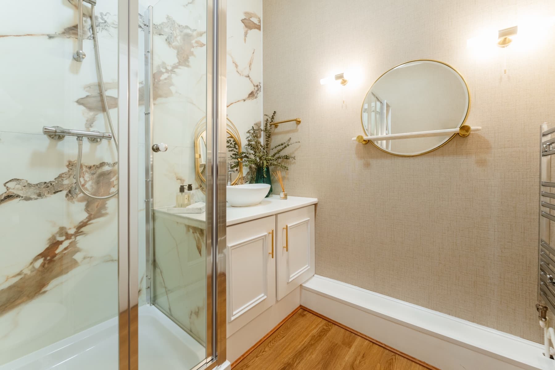 Marble walk-in shower and vanity with a round mirror